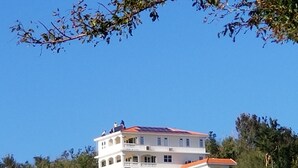 Ein mehrstöckiges Gebäude mit Balkonen, umgeben von Bäumen.