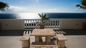Eine Terrasse mit Tisch und Bänken mit Blick auf ein Gewässer.