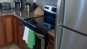 Eine Küche mit Holzausstattung, einem Edelstahlkühlschrank, einer Mikrowelle, einem Toaster und einer Kaffeemaschine.