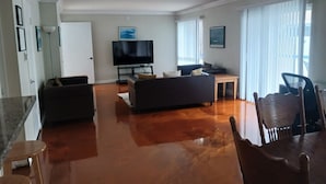 A living room with a sofa, a TV, a dining table, and chairs.