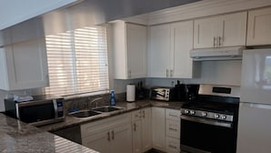A modern kitchen with white cabinets, granite countertops, a stove, microwave, and a toaster.
