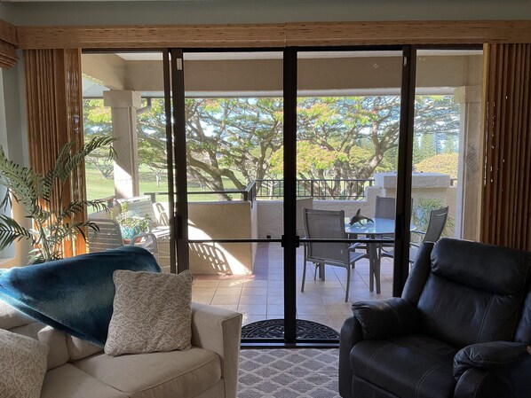 A room with a sliding glass door leading to an outdoor patio area with a pool, chairs, and a table.