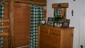 Een houten dressoir met laden, een klok en een klein plankje met diverse spullen.