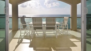 An open balcony with a table and chairs, offering a view of the sea and a boat in the distance. - Luxurious Oceanview Condo in Cozumel (Cozumel, Centre)