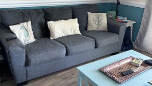A living room with a grey sofa, a light blue coffee table, and a teal wall. - La Casita-Oceanfront Oasis with Great Views (Carolina Beach)