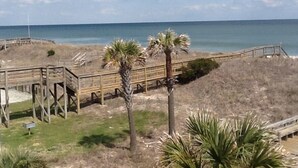 A beach area with wooden walkways, palm trees, and a view of the ocean. - La Casita-Oceanfront Oasis with Great Views (Carolina Beach)
