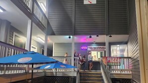 A multi-level indoor space with a staircase, wooden benches, and umbrellas.