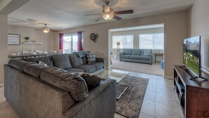 A modern living room with a sectional sofa, a flat-screen TV, ceiling fans, and a dining area with a table and chairs. - PRIVATE POOL - NEW EVERYTHING! Be our guest! (Scottsdale)