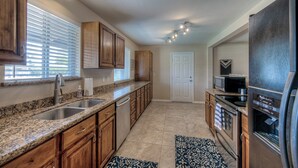 A kitchen with granite countertops, wooden cabinets, a stainless steel refrigerator, and a microwave. - PRIVATE POOL - NEW EVERYTHING! Be our guest! (Scottsdale)