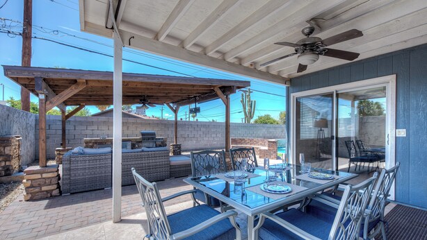An outdoor patio with a glass table, blue cushioned chairs, a grill, and a ceiling fan. - PRIVATE POOL - NEW EVERYTHING! Be our guest! (Scottsdale)