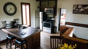 Une cuisine dotée d’un îlot central, d’appareils électroménagers en acier inoxydable et d’un escalier en bois.