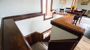 Un escalier en bois, doté d’une rampe, mène à un espace repas comprenant des chaises et une table.