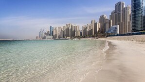 A beach with clear water and a city skyline in the background. - * Stunning! 5*- 4 BR-Oceanfront-Apartment-Private Beach- Ocean Views*  (Dubai)