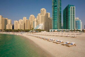 A beachside hotel with rows of sun loungers, a sandy beach, and high-rise buildings in the background. - * Stunning! 5*- 4 BR-Oceanfront-Apartment-Private Beach- Ocean Views*  (Dubai)