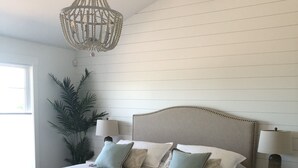 Un dormitorio amplio con una cama grande, dos mesitas de noche, un candelabro y una planta en maceta.