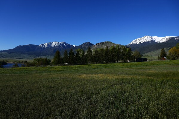 A mountainous landscape with a field in the foreground and a small building in the distance.