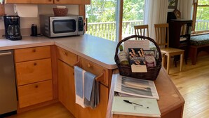 A kitchen with wooden cabinets, a microwave, a coffee maker, and a dining area with a table and chairs.