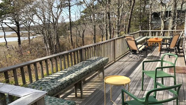 A wooden deck with a bench, chairs, and a small table.