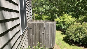 A wooden fence with a gate, a brick pathway, and lush greenery in the background.