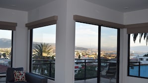 Ein modernes Wohnzimmer mit großen Fenstern, einem Sofa und Blick auf eine Stadtansicht.