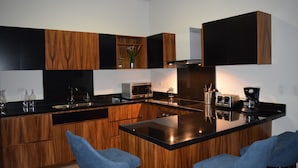 Eine moderne Küche mit Holzschränken, einer schwarzen Arbeitsplatte und zwei blauen Barhocker.