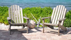 Two Adirondack chairs with a beach view and a decorative object between them.