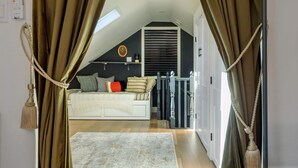 Quarto com cama, janela, ventilador de teto e termostato fixado na parede.