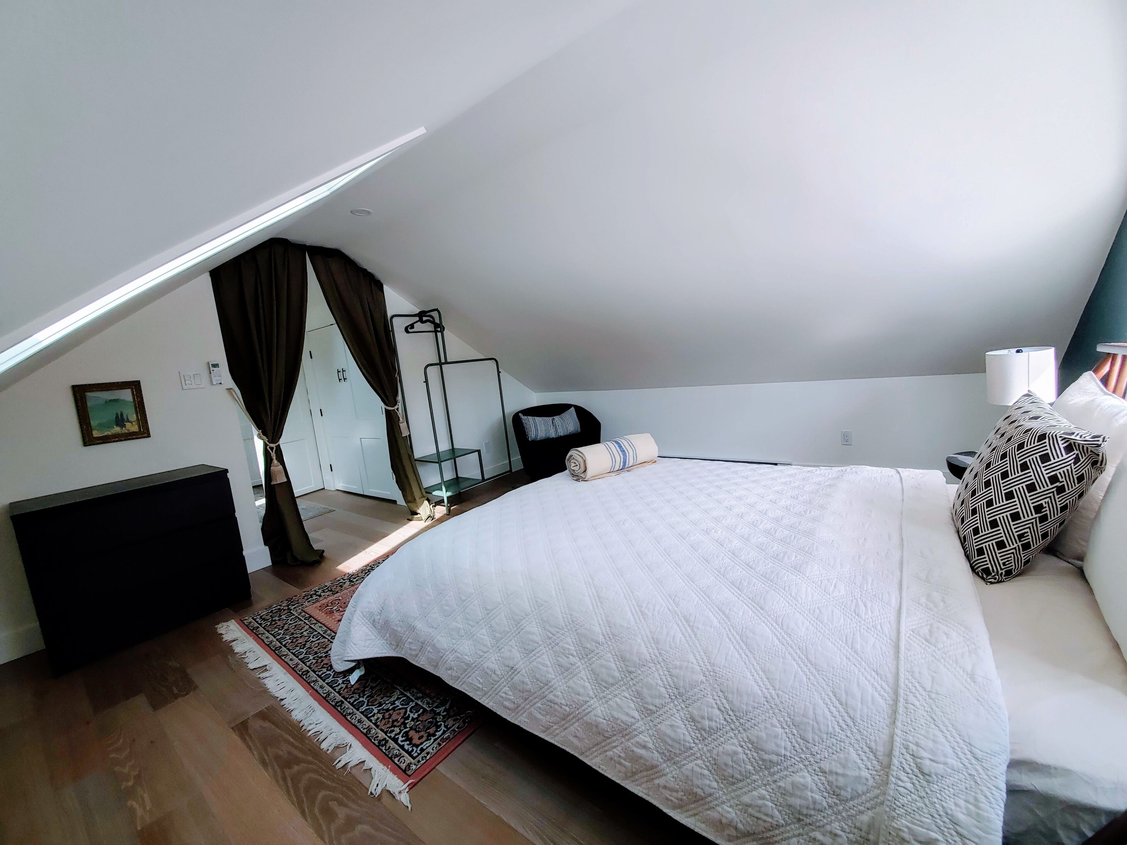 Un dormitorio con una cama grande, una mesita de noche, una lámpara, un armario y un sillón colgante.