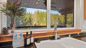 A bathroom with a large window, a sink, and a wooden bench.