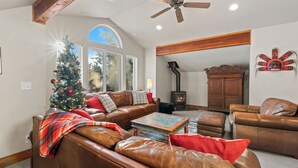 A living room with leather sofas, a coffee table, a fireplace, and a Christmas tree.