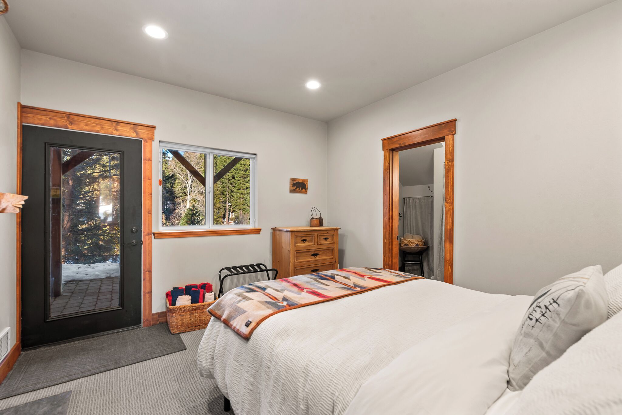 Un dormitorio con cama, cómoda, ventana, puerta y espejo.