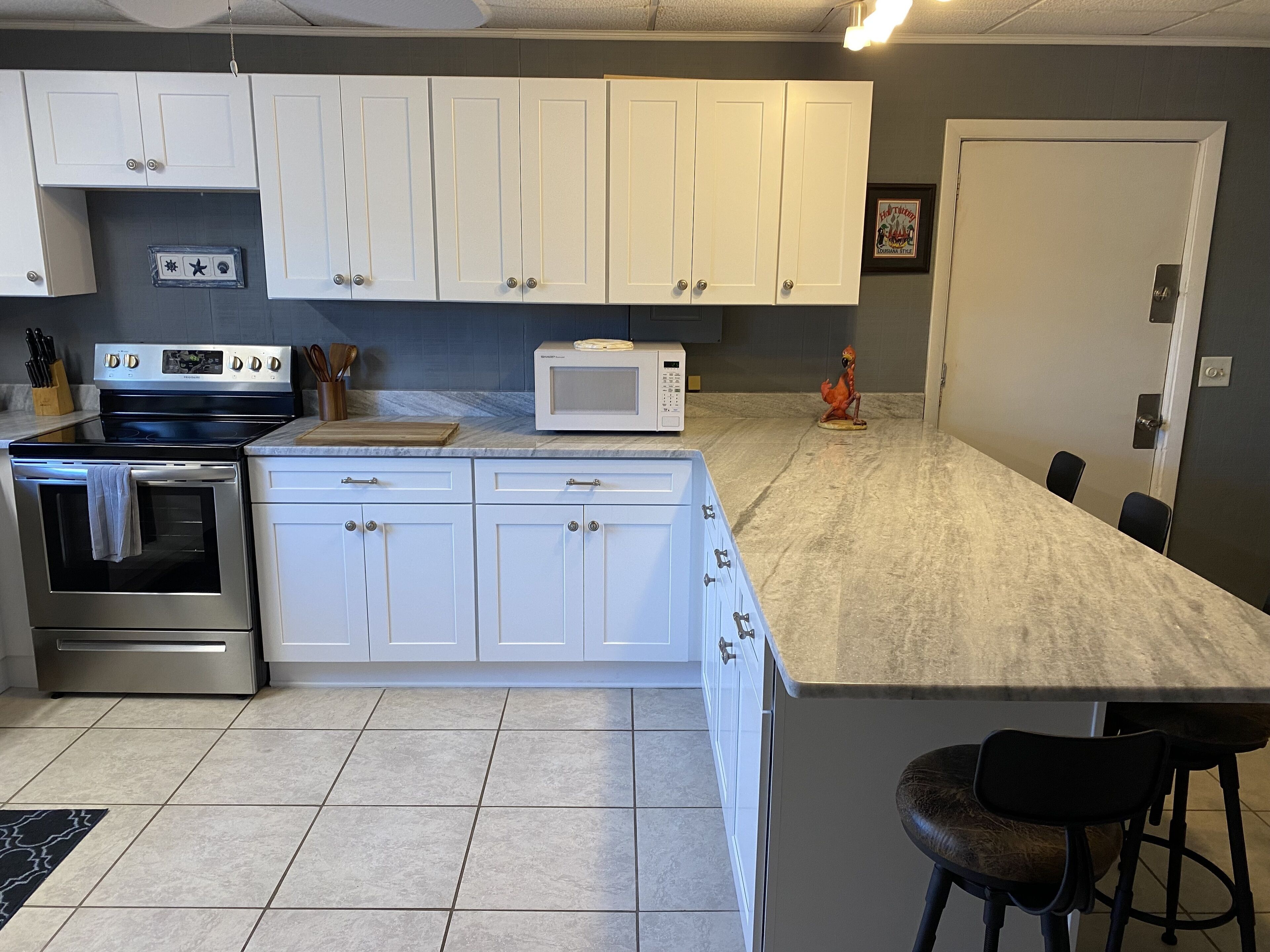 A kitchen with white cabinets, a stainless steel stove, a microwave, and a small statue.