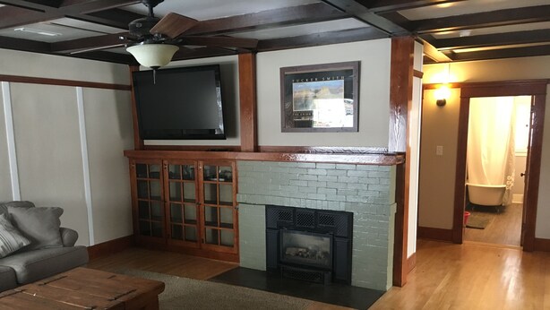 A living room with a fireplace, a sofa, a coffee table, and a flat-screen TV mounted above the fireplace.