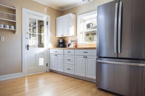 A kitchen with white cabinets, a stainless steel refrigerator, and a coffee maker on the counter.
