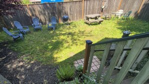 Een achtertuin met een houten terras, een barbecue en tuinmeubilair.