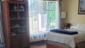 Een slaapkamer met een bed, een houten kast, een raam met gordijnen en een kamerbreed tapijt met dessin.
