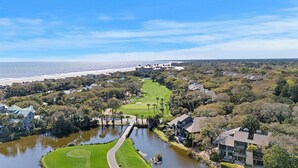 A golf course with a water feature, surrounded by residential buildings and a beach.