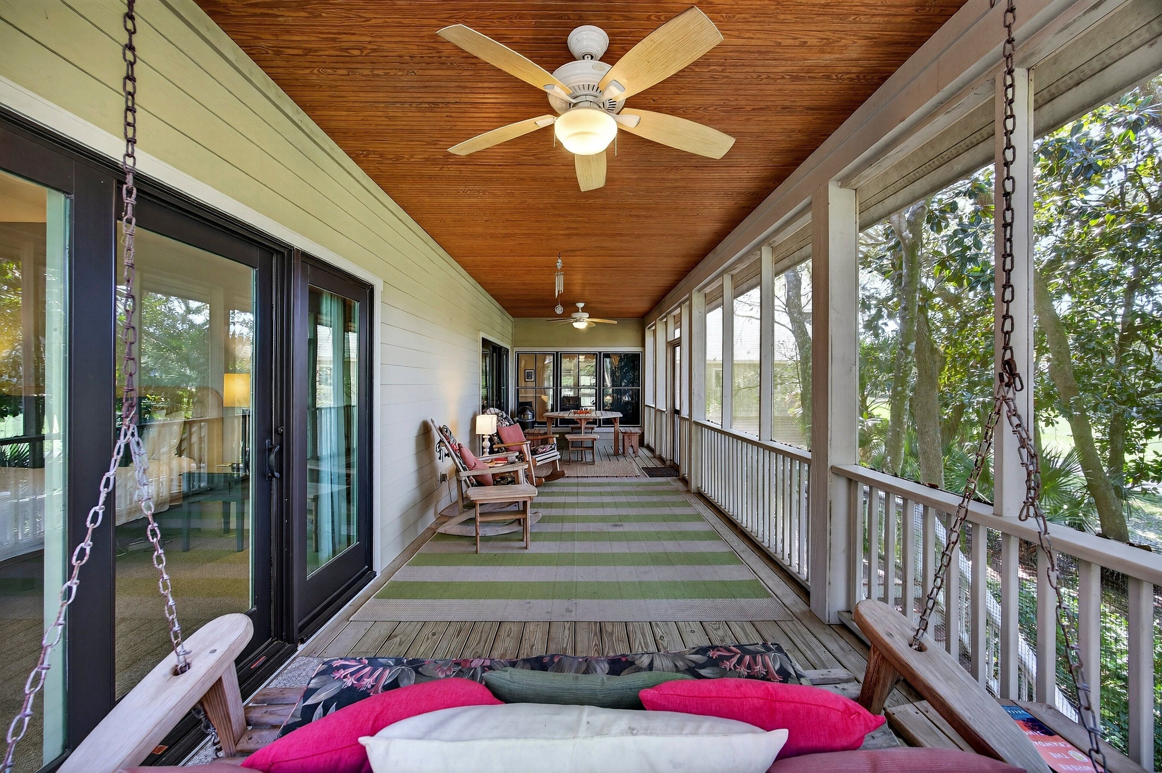 A covered porch with a ceiling fan, wooden flooring, and a view of the outdoors.