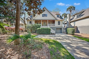 A two-story house with a front porch, a driveway, and a well-maintained lawn.