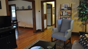 A living room with a television, a grey armchair, a bookshelf, and a potted plant. - Fantastic duplex in the Historic District (Minneapolis)