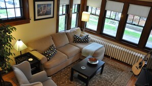 A living room with a sofa, armchair, coffee table, lamp, guitar, and a radiator. - Fantastic duplex in the Historic District (Minneapolis)