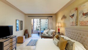 A hotel room with a bed, a TV, a sofa, a lamp, and a balcony with a view of buildings. -  Villa La Estancia 1509 Premium Ocean View! (Cabo san Lucas)