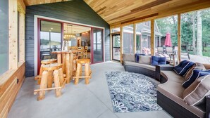 A spacious living area with a wooden ceiling, a large sofa, and a dining table with stools.