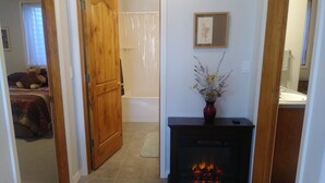 A hallway with a wooden door, a fireplace with a vase of flowers, and a bed with a teddy bear. - Spacious Quiet Country Home With Stunning Views from Private Patio (Inkom)
