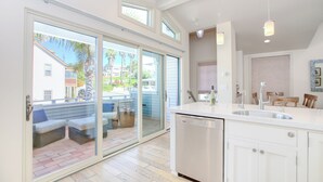 A modern kitchen with a dishwasher, a sink, and a dining area with a table and chairs. - Sunsetter in Avila Beach - 2 min walk to beach, located in Ocean 17 (Avila Beach)