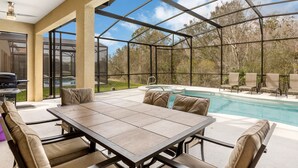 A covered outdoor area with a pool, seating, and a grill.