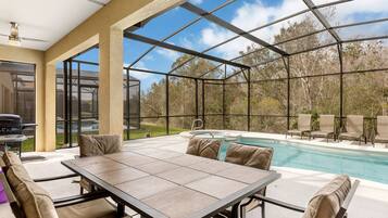 Un espacio al aire libre techado con piscina, asientos y una parrilla.
