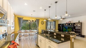 A modern kitchen with a central island, white cabinetry, and pendant lighting.