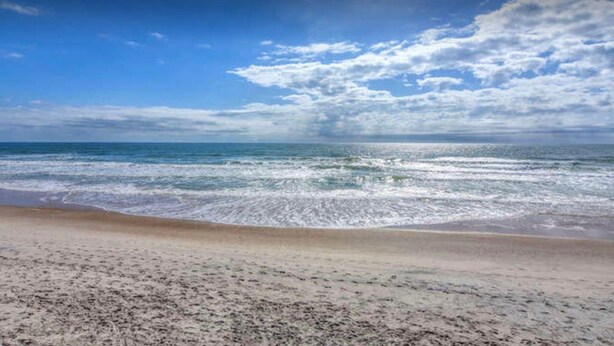 A beach with a sandy shore and a view of the ocean. - Your Perfect Beach House (Surf City)