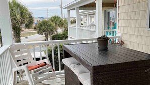 A wooden deck with a wicker bar and white rocking chairs. - Your Perfect Beach House (Surf City)